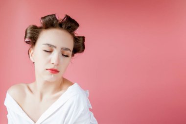 Yüzüne dokunmadan bir maske ve curlers ile güzel genç kız.