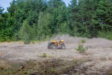 Adam sarı bir dörtlü Atv kumlu bir ön planda tüm arazi aracı sürme