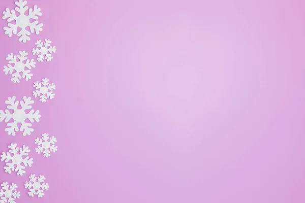 Modello invernale realizzato con fiocchi di neve e su sfondo rosa. Concetto natalizio. Piatto. Copia spazio per il testo — Foto Stock