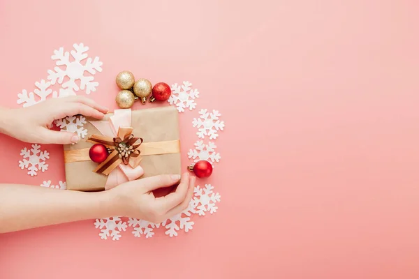 Vrouwelijke handen houden aanwezig met strik op roze achtergrond. Feestelijke achtergrond voor vakantie: Verjaardag, Valentijnsdag, Kerstmis, Nieuwjaar. Vlakke plaat — Stockfoto