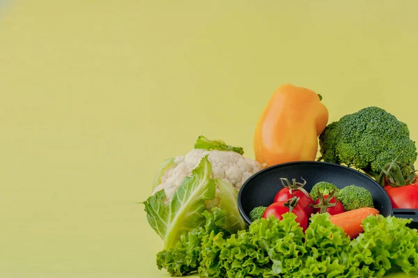 Verse groenten op koekenpan op gele achtergrond. Veganistisch en genezend — Stockfoto