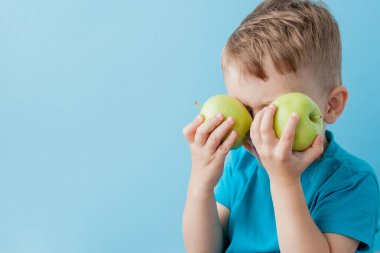 Little Boy mavi arka plan, diyet ve iyi bir sağlık konsepti için egzersiz elinde bir Elma holding