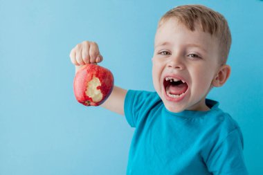 Bebek kucağında kırmızı elma, mavi arka plan, yemek, diyet ve sağlıklı beslenme konsepti