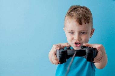 Küçük çocuk çocuk 2-3 yaşında mavi giysiler giyen gameson mavi arka plan çocuk stüdyo portre için el joystick tutun. İnsanlar çocukluk yaşam tarzı kavramı. Kopya alanı yla alay edin