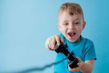 Küçük çocuk çocuk 2-3 yaşında mavi giysiler giyen gameson mavi arka plan çocuk stüdyo portre için el joystick tutun. İnsanlar çocukluk yaşam tarzı kavramı. Kopya alanı yla alay edin