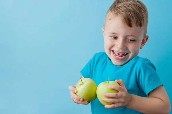 Menino segurando uma maçã em suas mãos sobre fundo azul, dieta e exercício para um bom conceito de saúde — Fotografia de Stock