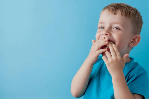 Little Boy Sostener y comer un plátano sobre fondo azul, comida, dieta y concepto de alimentación saludable — Foto de Stock