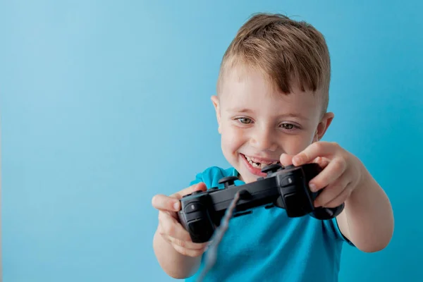 Bambino bambino 2-3 anni indossa vestiti blu tenere in mano joystick per giochisu sfondo blu bambini studio ritratto. Persone concetto di stile di vita infantile. Falsificare spazio di copia — Foto Stock