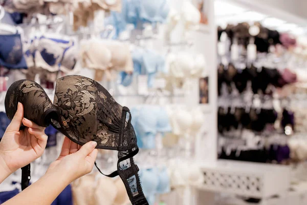 Las manos de las mujeres están sosteniendo una lencería en la tienda ropa interior de mujer en el centro comercial — Foto de Stock