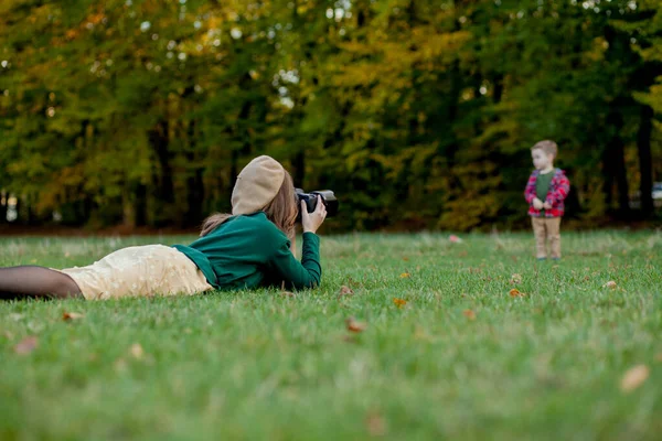 Женщина-фотограф фотографирует ребенка на улице в парке — стоковое фото