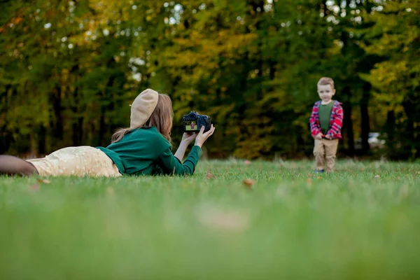 Mujer fotógrafa fotografiando al niño para pasar fuera en t — Foto de Stock