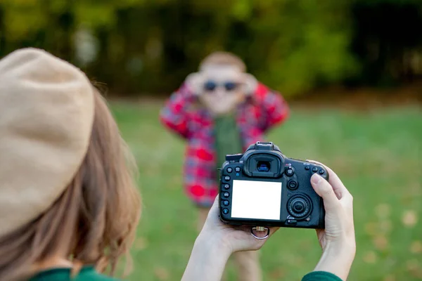 Женщина фотограф фотографирует ребенка, чтобы провести на улице в т — стоковое фото