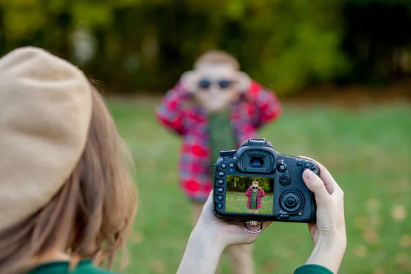 Женщина фотограф фотографирует ребенка, чтобы провести на улице в т — стоковое фото