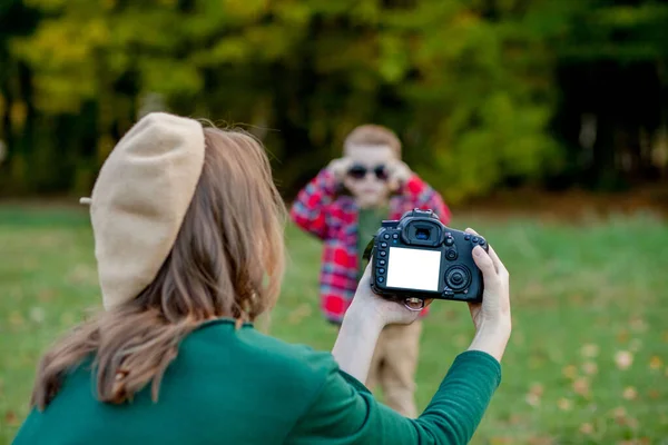 Kadın fotoğrafçı dışarıda geçirmek için çocuğun fotoğrafını çekiyor. — Stok fotoğraf