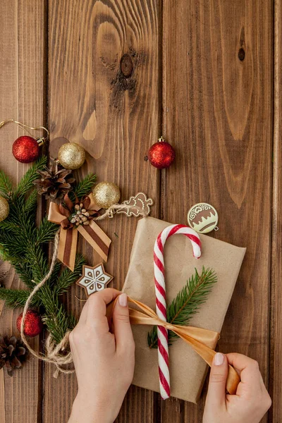 Kvinnans händer inslagning julklapp, närbild. Oförberedda jul presenterar på trä bakgrund med inredning element och objekt, ovanifrån. Jul eller nyår DIY förpackning Koncept. — Stockfoto