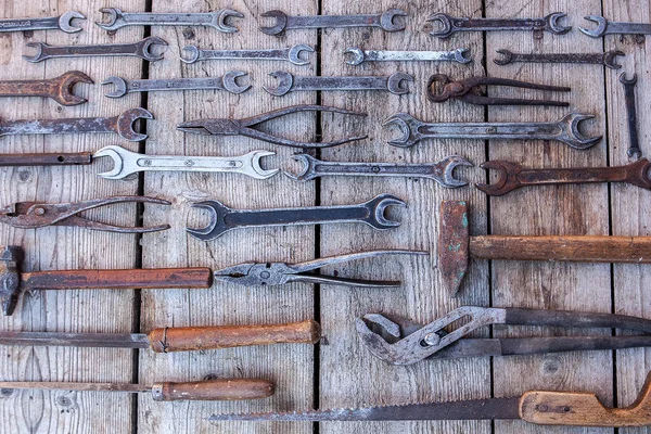 金属扳手生锈的工具躺在黑色的木桌上。锤子, 凿子, 钢锯, 金属扳手。肮脏的一套手工工具在木面板老式背景与工具 — 图库照片