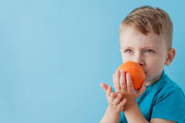 Little Boy mavi arka plan, di elinde bir Portakal Holding