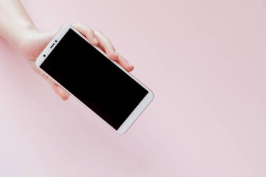 Pembe arka planda bir kadının elinde modern cep telefonu