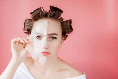 Yüzüne dokunmadan bir maske ve curlers ile güzel genç kız.
