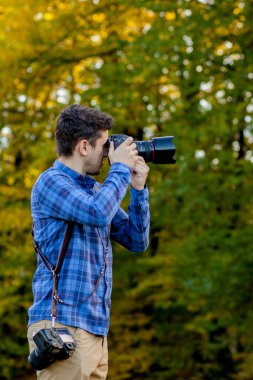 Profesyonel fotoğrafçı omuz bandında iki kamerayla iş başında.