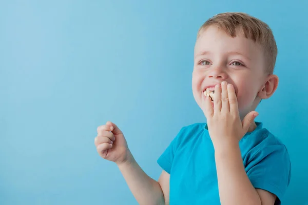 Little Boy Håller och äter en banan på blå bakgrund, mat — Stockfoto