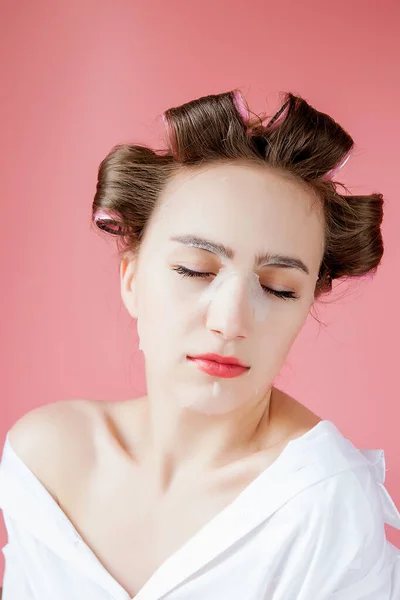 Mooi jong meisje met een masker en krulspelden die haar gezicht aanraken. — Stockfoto