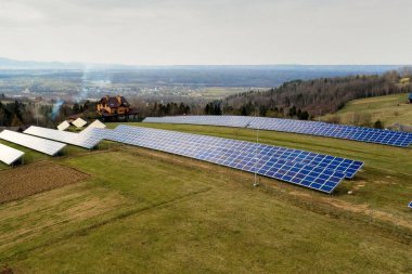 Yeşil çimen arka planında yenilenebilir temiz enerji üreten büyük solar fotoğraf voltaik panelleri sisteminin havadan görünüşü