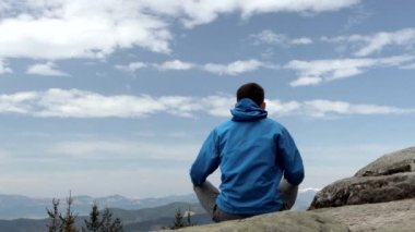 Harika bir dağ yerinde yoga yapan genç adam, yeni bir çağ, enerji, meditasyon ve sağlık, lotus pozisyonunda gülümseyen genç adam..