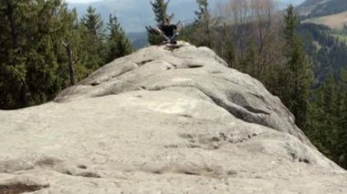 Genç adam kayalık dağın tepesinde koşuyor.