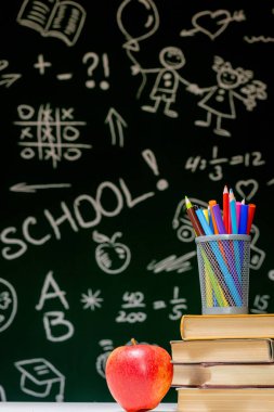 Kitaplar, kalemler ve beyaz masanın üzerindeki elmayla okula geri dön.