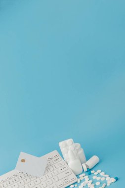 İlaç ve klavyeli alışveriş arabası oyuncağı. Haplar, su toplayan paketler, tıbbi şişeler, termometre, mavi arka planda koruyucu maske. - Evet. Sağlık ve internet alışverişi. Metniniz için en üstteki görünüm.