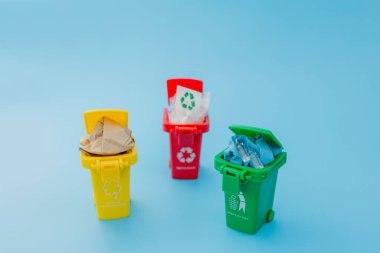 Sarı, yeşil ve kırmızı geri dönüşüm kutularında mavi arka planda geri dönüşüm sembolü var. Şehri düzenli tutar, geri dönüşüm sembolünü bırakır. Doğa koruma kavramı.