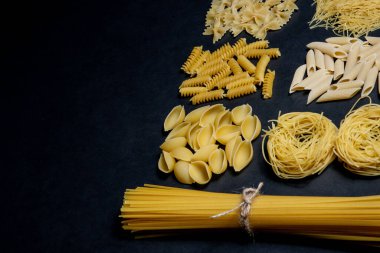 Siyah zemin üzerinde çeşitli makarna türleri. Üst Manzara. Çeşitli makarna çeşitleri. Tasarım için alanı kopyala