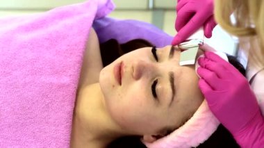 Kozmetik uzmanı, güzellik salonundaki genç ve güzel bir kadının yüz derisini ultrasonik olarak soyuyor.
