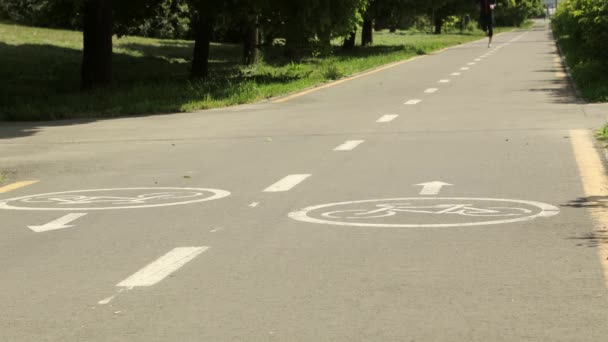 自行车路上的自行车标志在公园里 女人在后面跑 — 图库视频影像