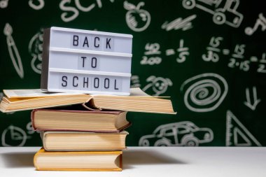 Kitap, kalem ve küre ile okul arka planına yeşil karatahta arka planında beyaz masa üzerinde.