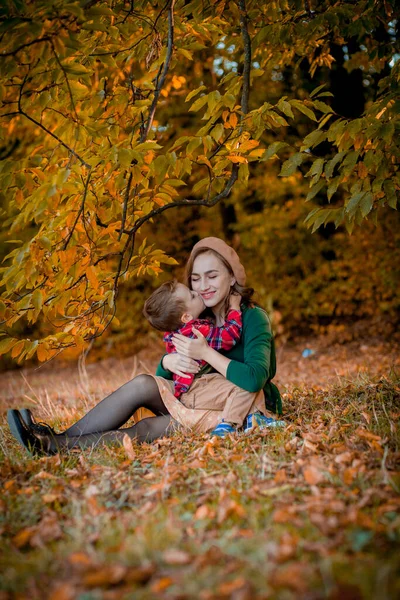 Szczęśliwa młoda matka bawiąca się i bawiąca ze swoim synkiem w słoneczny ciepły jesienny dzień w parku. Szczęśliwa koncepcja rodziny, Dzień Matki — Zdjęcie stockowe