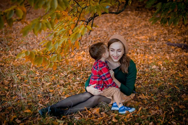 Щаслива молода мати бавиться зі своїм маленьким сином у теплий осінній день у парку. Щаслива сімейна концепція, День матері — стокове фото