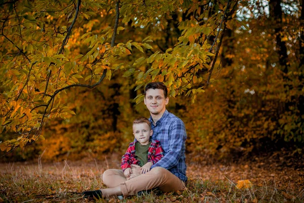 Šťastná rodina se baví venku v podzimním parku. Otec a syn proti žluté rozmazané listí pozadí. Šťastný rodinný koncept, Den otců — Stock fotografie