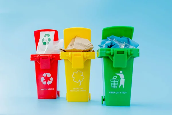 Papeleras de reciclaje amarillas, verdes y rojas con símbolo de reciclaje sobre fondo azul. Mantén ordenada la ciudad, deja el símbolo del reciclaje. Concepto de protección natural — Foto de Stock