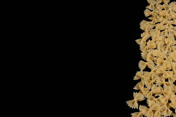 Farfalle raw pasta on black background. Cooking concept. Top view with copy space. — Stock Photo, Image