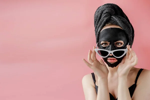 Jonge Vrouw Bril Apppling Zwarte Cosmetische Stof Gezichtsmasker Roze Achtergrond — Stockfoto