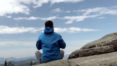 Harika bir dağ yerinde yoga yapan genç adam, yeni bir çağ, enerji, meditasyon ve sağlık, lotus pozisyonunda gülümseyen genç adam.