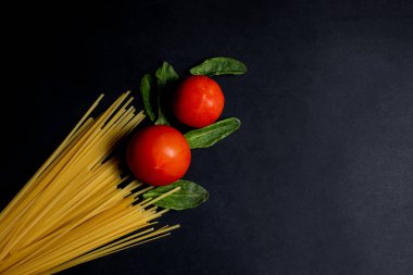 Spagetti macunu, domates ve diğer ürünler koyu arka planda yemek pişirmek için. Metin için boşluk, üst görünüm.