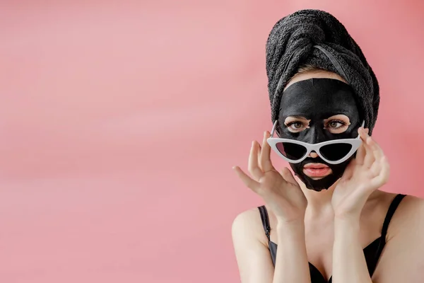 Jonge Vrouw Bril Apppling Zwart Cosmetische Stof Gezichtsmasker Roze Achtergrond — Stockfoto