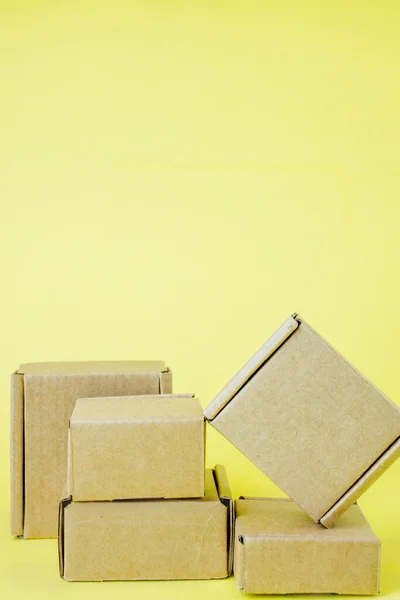 黄色の背景に様々なサイズの段ボール箱 — ストック写真