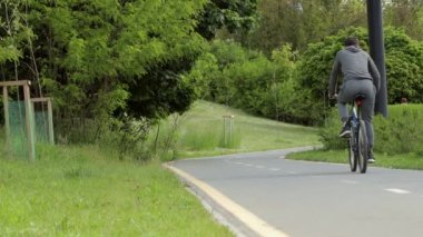 Şehir yolunda bisiklet sürme, şehir caddesinde yol işaretinin yanında bisiklet süren tanınmayan bir bisikletlinin gölgesi. Sağlıklı bisiklet yaşam tarzı