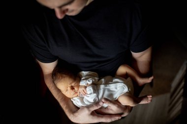 Babası 15 günlük oğlunu siyah arka planda tutuyordu.