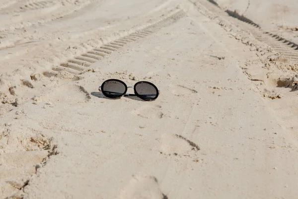 Vista superior de gafas de sol en la playa cerca del mar azul con arena — Foto de Stock