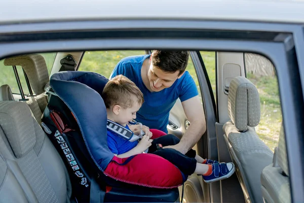 Father putting baby in safety car seat dad and child together family road trip vacations lifestyle infant kid transportation rear-facing.